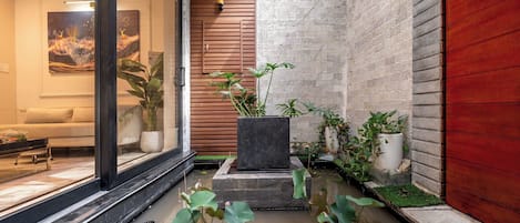 Un interior moderno con una jardinera de piedra, una pared de madera y una puerta de cristal.