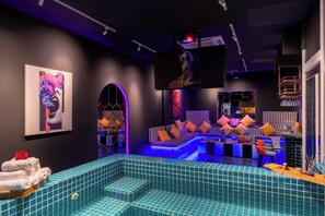 A modern interior with a pool area, seating, and a flat-screen TV. - Tropical Pool Villa D1 with 5 bedrooms (Tan Dinh)