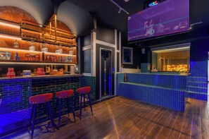 A bar area with stools, a shelf with bottles, a television screen, and a tiled counter. - Tropical Pool Villa D1 with 5 bedrooms (Tan Dinh)