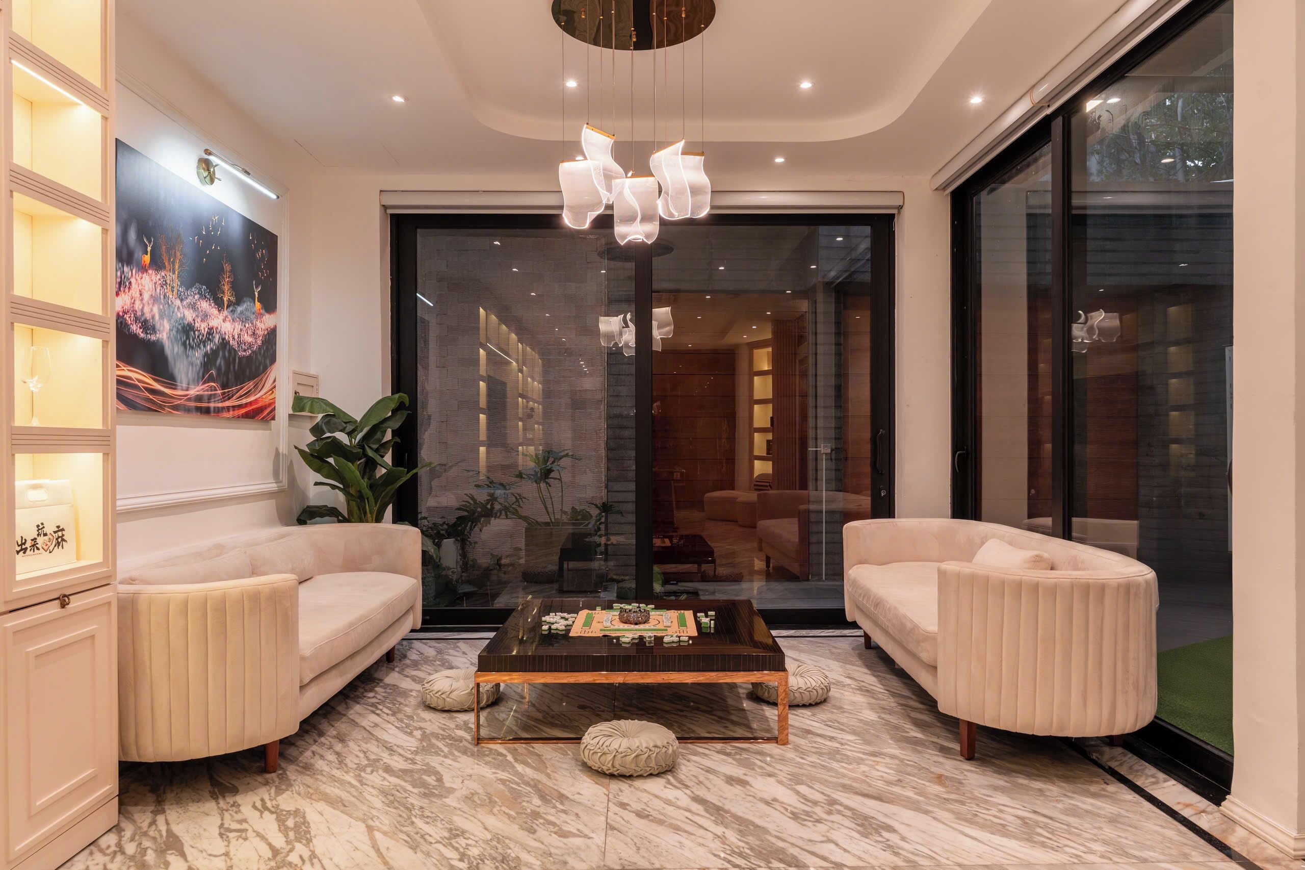 A modern living room with a marble floor, a coffee table, two sofas, a large painting, and a glass door leading to another room.