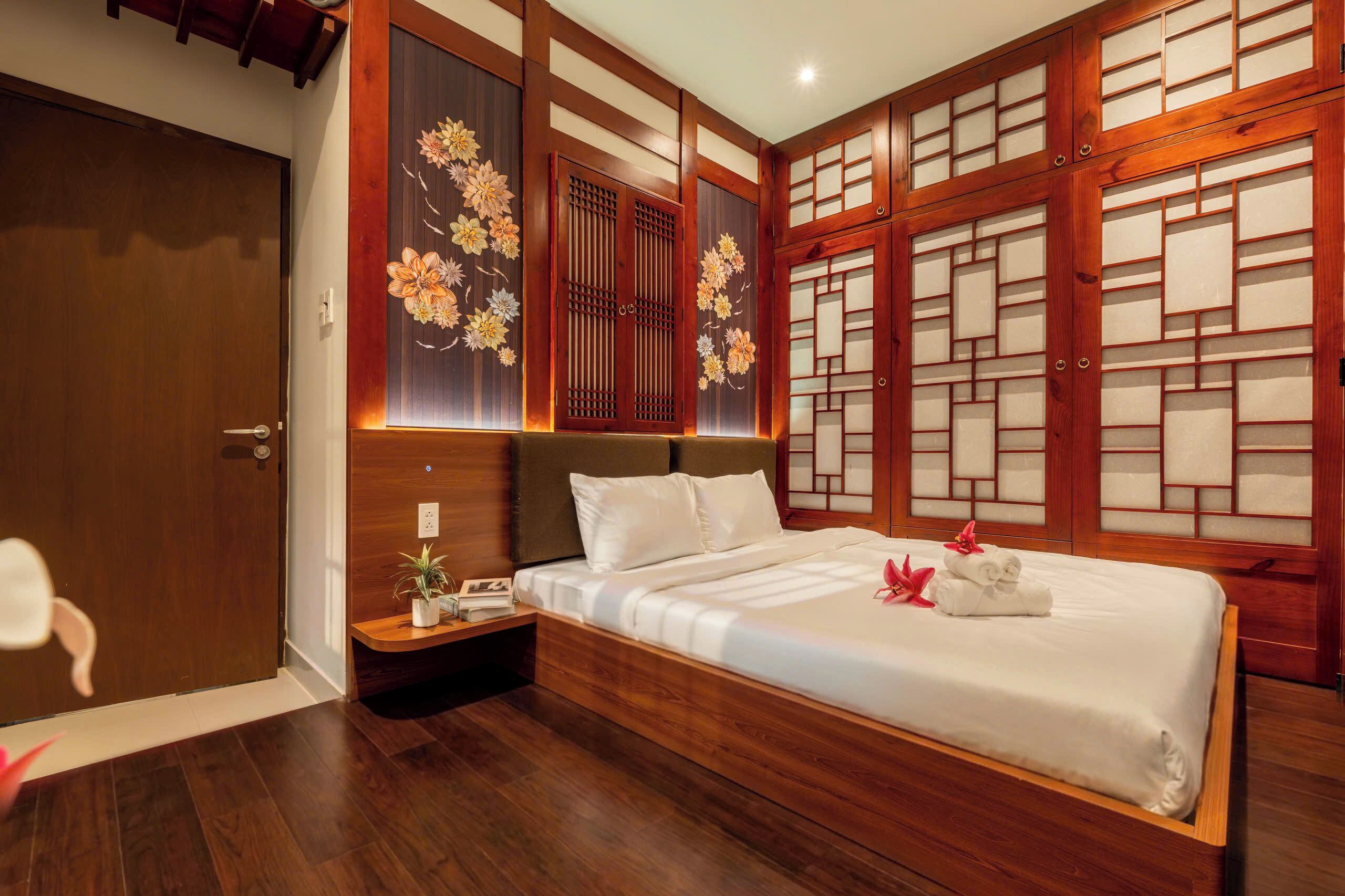 A traditional Japanese-style bedroom with a wooden bed frame, a nightstand, and a decorative wall panel.