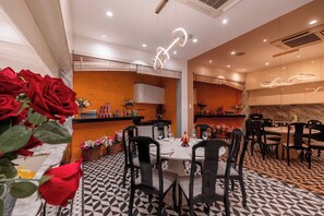 A dining area with a geometric patterned floor, black chairs, and a central table with a vase of red roses. - Tropical Pool Villa D1 with 5 bedrooms (Tan Dinh)