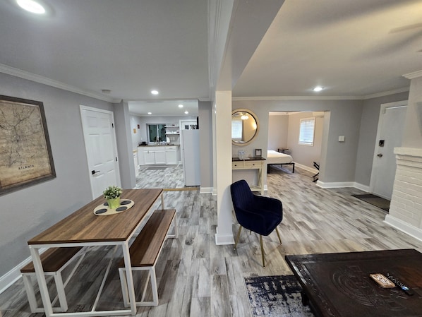 A modern interior with a dining area, a seating area, a kitchen, and a bedroom.
