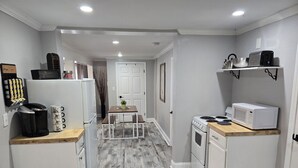 A compact kitchen with white appliances, a wooden dining table, and a small countertop.