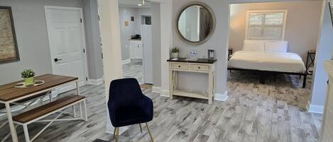 A bedroom with a bed, a desk, a chair, a dresser, and a mirror.