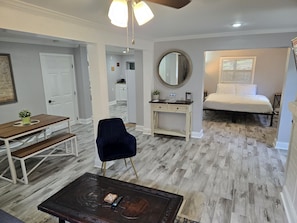A bedroom with a bed, a desk, a chair, a dresser, and a mirror.