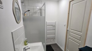 A bathroom with a white sink, mirror, and shower. - Studio Cosy Centre Valenciennes Station and streetcar on foot (Valenciennes)