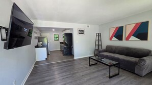 Un soggiorno moderno con TV a schermo piatto, un divano grigio e opere d'arte astratte alle pareti.