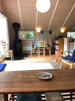 Ein gemütliches Blockhaus-Interieur mit einem Holztisch, Stühlen, einem Bücherregal und einem Kamin.