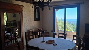 Un comedor con una mesa redonda, sillas, una araña y vistas amplias a través de grandes ventanales.