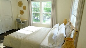 Een slaapkamer met een bed, een bureau en een raam met gordijnen.