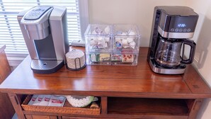 Ein Holztisch mit einer Kaffeemaschine, einer Keurig-Kaffeemaschine und einer Kapselbox für Kaffee.