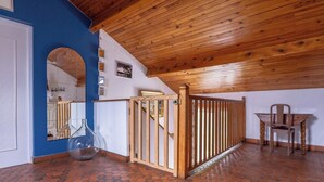 Une pièce avec un plafond en bois, un mur bleu, un sol carrelé, une chaise en bois et un portail.