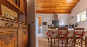 A wooden interior with a dining table, chairs, and a kitchen area with a microwave and stove. - Les trois chênes - SAYAT (SAYAT)