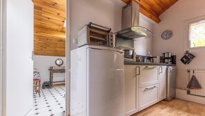 Une cuisine équipée d’un four encastré, d’une cuisinière, d’un four à micro-ondes et d’un porte-casseroles suspendu.