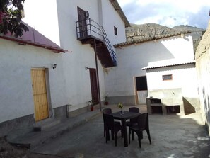 A courtyard with a table and chairs, a small staircase, and a door.