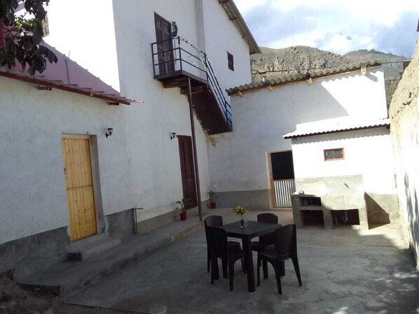 A courtyard with a table and chairs, a small staircase, and a door.