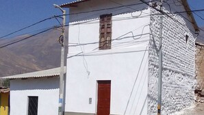 Un edificio blanco con puerta roja, una ventana pequeña y un poste de electricidad con cables.
