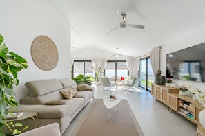 Ein modernes Wohnzimmer mit einer Couch, einem Couchtisch und einem Fernseher auf einer Holzkommode.