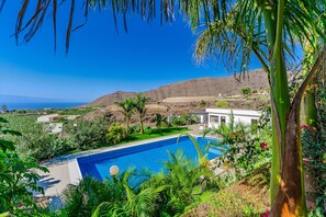 Ein Pool, umgeben von üppiger Vegetation mit Blick auf das Meer.