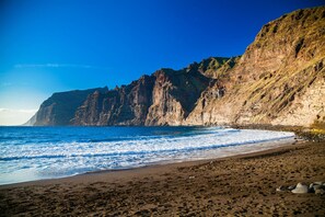 Eine Küstenlandschaft mit einem Felsen, einem Sandstrand und dem Meer.