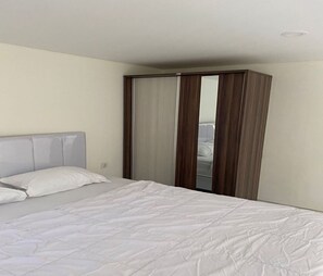 A bedroom with a bed, a wardrobe, and a mirror.