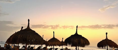 Ein Strand mit Strohdächern und Liegestühlen.