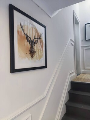 A staircase with a framed artwork of a deer head on the wall. - Apartment in Belfast City (3) (Belfast)