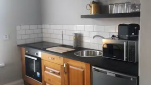 A kitchen with wooden cabinets, a black countertop, a sink, a microwave, and a dishwasher. - Apartment in Belfast City (3) (Belfast)