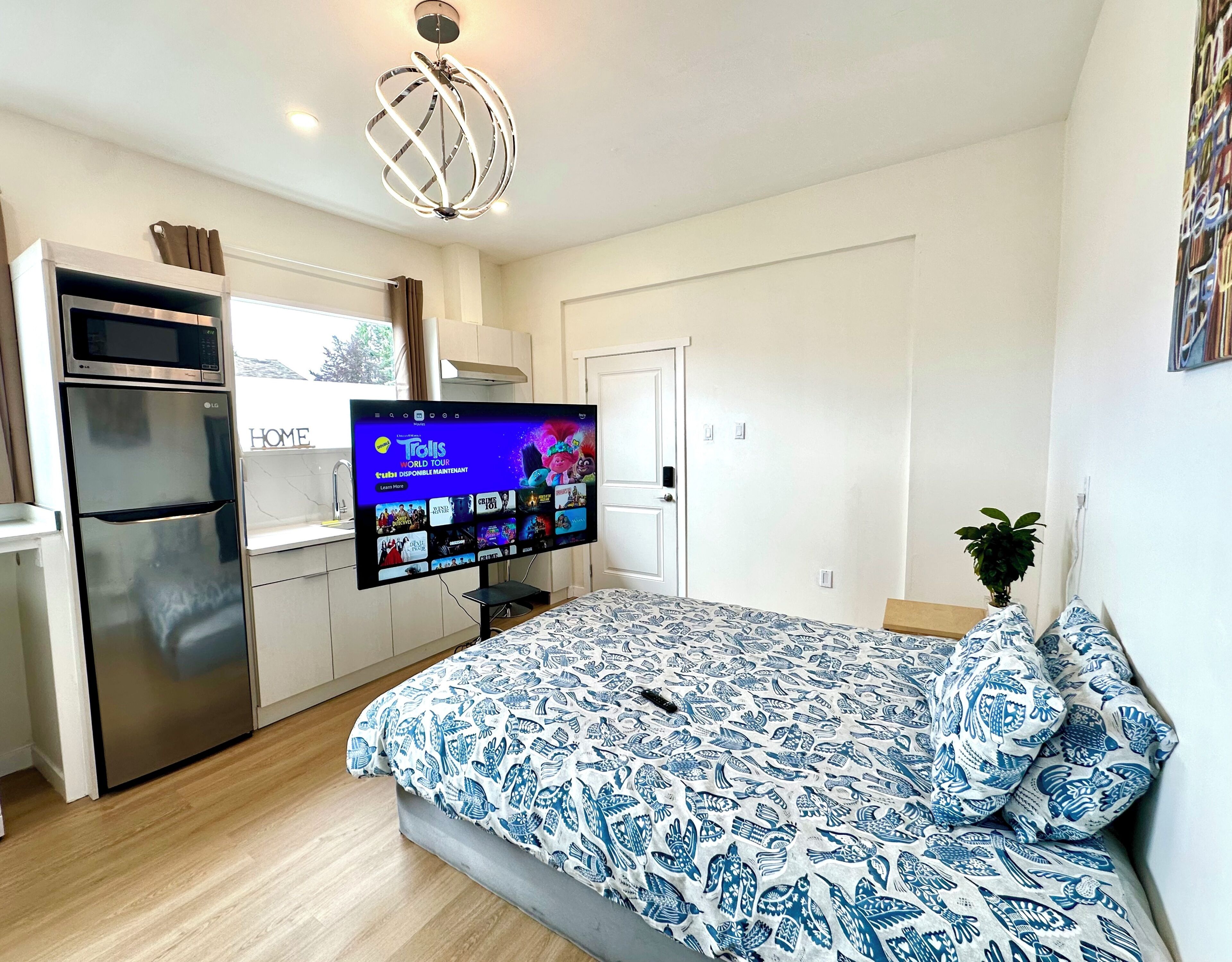 Ein modernes Schlafzimmer mit Bett, Flachbildfernseher, Kühlschrank und Essbereich.