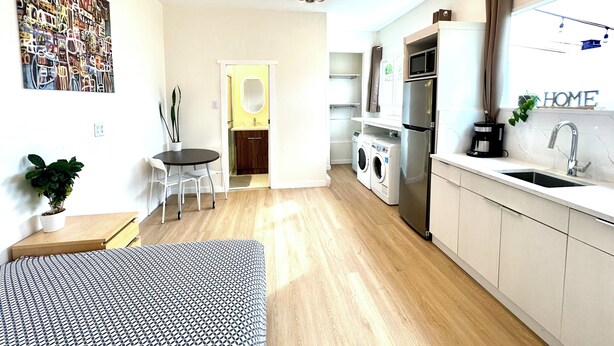 Eine moderne Küche mit Einbauofen, Mikrowelle und Spüle. Ein Essbereich mit Tisch und Stühlen sowie eine kleine Sitzecke mit einer Couch vorhanden.
