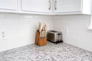 Eine Küche mit weißen Schränken, einer Granitarbeitsplatte, einem Messerblock und einem Toaster.
