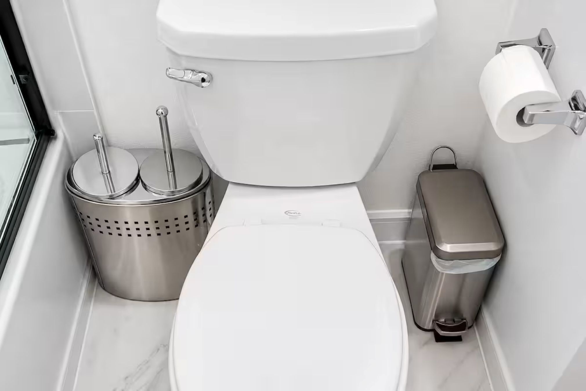 Une salle de bain moderne équipée de toilettes, d’un bidet, d’un porte-rouleau de papier toilette et d’une poubelle.