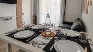 A dining area with a table set for two, a television mounted on the wall, and an air conditioning unit. - Casa DiLauNa - Cozy apartment in the heart of Albufeira - Portugal (Albufeira)