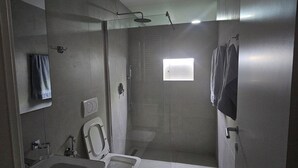 Moderni kylpyhuone, jossa on wc, pesuallas, suihku ja pieni ikkuna.
