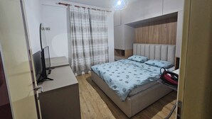 Makuuhuoneessa on sänky, televisio, vaatekaappi ja verho.