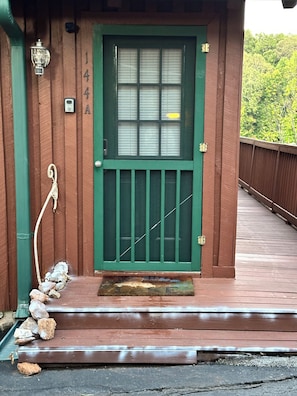 A wooden building with a green door, a mailbox, and a stone step leading to the entrance.