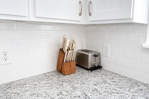 Eine Küche mit weißen Schränken, einer Granit Arbeitsplatte, einem Messerblock und einem Toaster.