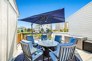 A patio with a round table, four chairs, and a large umbrella. - 100 Yards to Beach! Fire Pit, 3 Decks, Dogs OK! (Navarre)