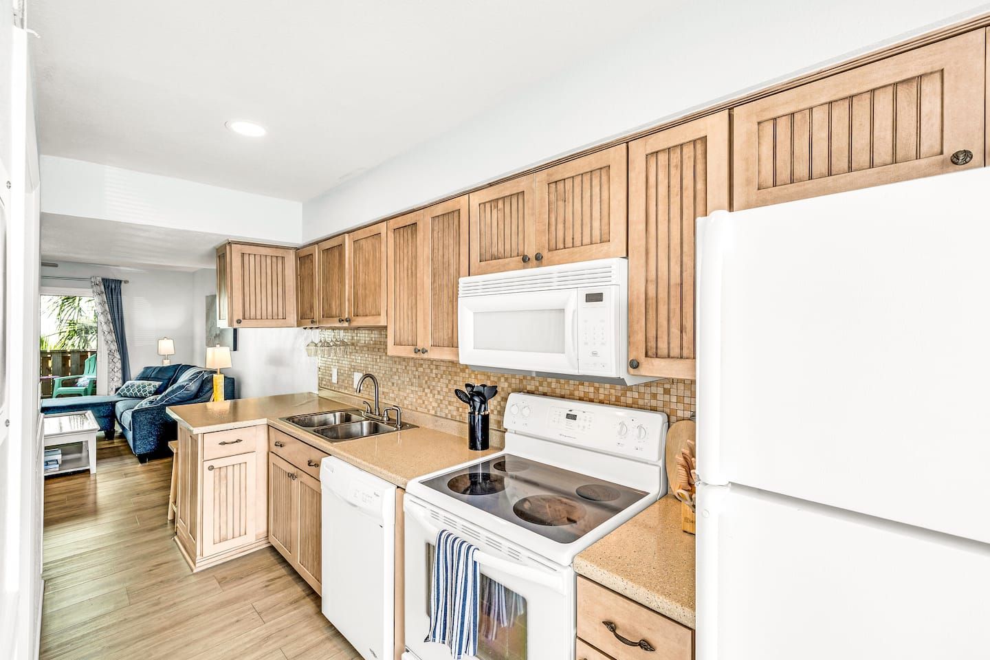 A modern kitchen with wooden cabinets, a white microwave, a stove, and a dishwasher.