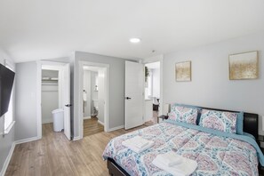 Un dormitorio con cama, armario, baño y un pasillo.