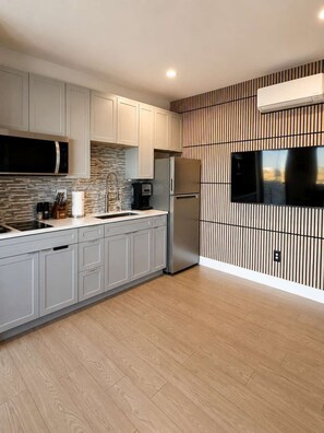 A modern kitchen with a built-in microwave, stainless steel refrigerator, and a flat-screen TV mounted on the wall. - The Dark Sky Haven, Luxe Casita, Views, Sleeps 2 (Page)