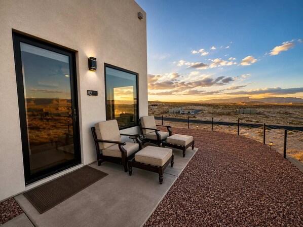 A balcony with outdoor seating, a view of the desert landscape, and a building with large windows. - The Dark Sky Haven, Luxe Casita, Views, Sleeps 2 (Page)