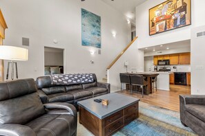 Ein modernes Wohnzimmer mit einer Ledersofa, einem Couchtisch und einer Küche im Hintergrund.