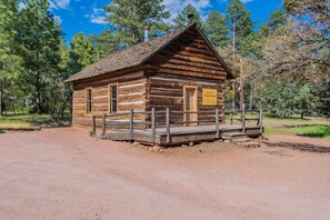 Una rustica baita di legno con portico, circondata da alberi.