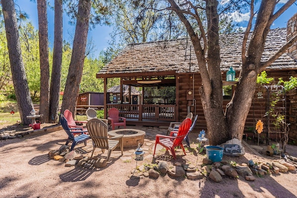 A rustic cabin with a fire pit, outdoor seating, and a covered porch.