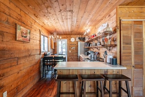 Un interno in legno con angolo cottura, sgabelli da bar e tavolo da pranzo.