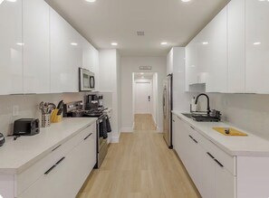 Een moderne keuken met witte kasten, een magnetron, een broodrooster en een spoelbak.