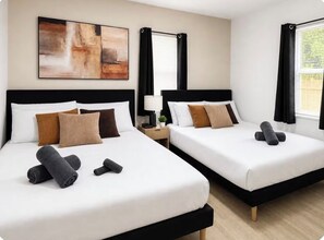 A hotel room with two beds, a nightstand, a lamp, and a painting on the wall. - Wilton Manors • Las Olas • Beach • Downtown FTL (Fort Lauderdale)