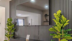 Un taulell de recepció amb un gran mirall, dues plantes en testos i un cartell.